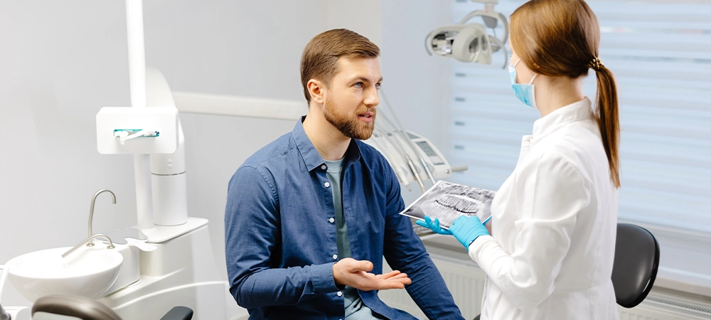 young attractive man visiting dentist, sitting in dental chair at modern light clinic