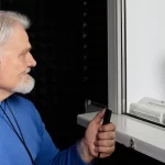audiologist doing hearing check-up to senior man in soundproof audiometric booth