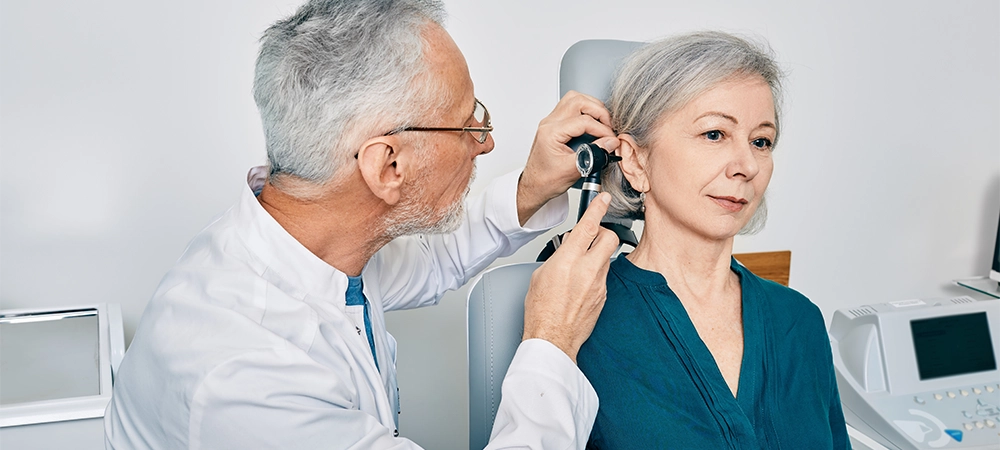 otolaryngologist doctor checking senior woman ear using otoscope