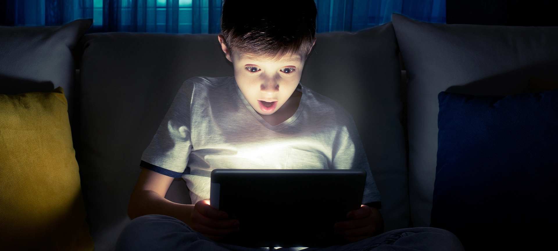 Boy using tablet pc at night. Boy with tablet computer in a dark room.