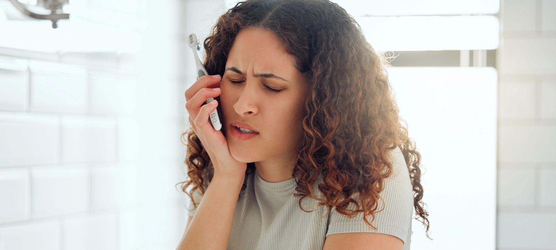 Pain, tooth ache and toothache from poor dental care, gum disease or bad personal hygiene routine in home bathroom. Stressed woman with cavity suffering and brushing teeth, cleaning mouth