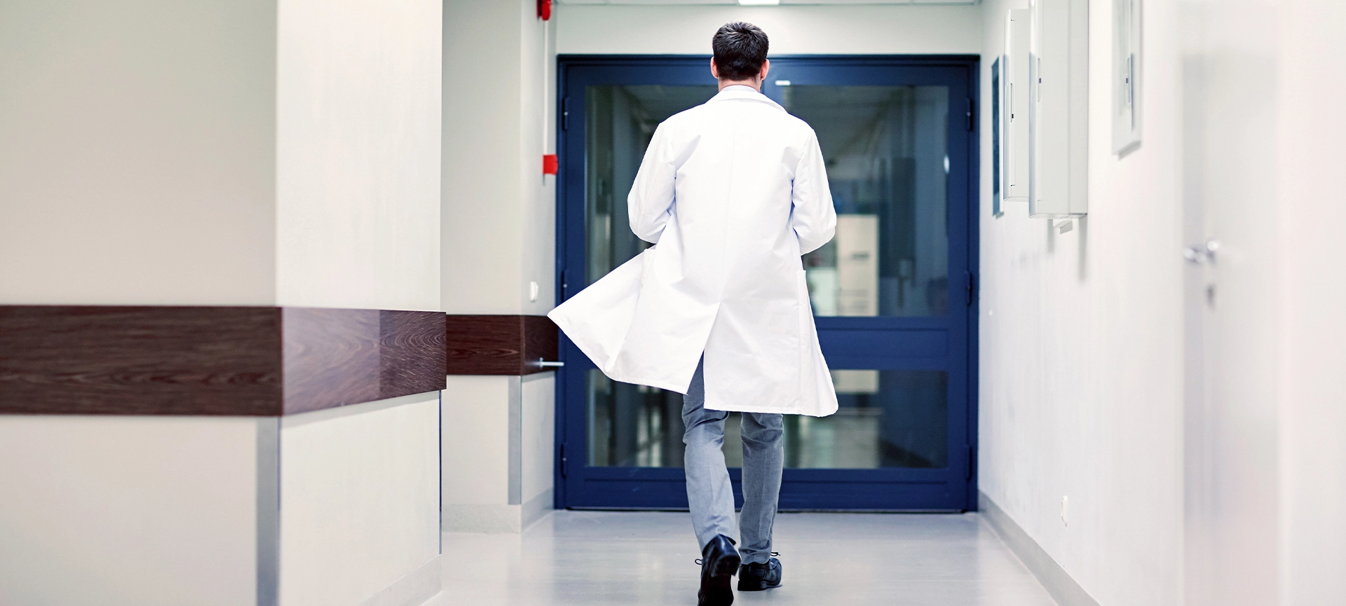 clinic, profession, people, healthcare and medicine concept - medic or doctor walking along hospital corridor