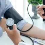 Doctor man is checking the blood pressure of the patient.