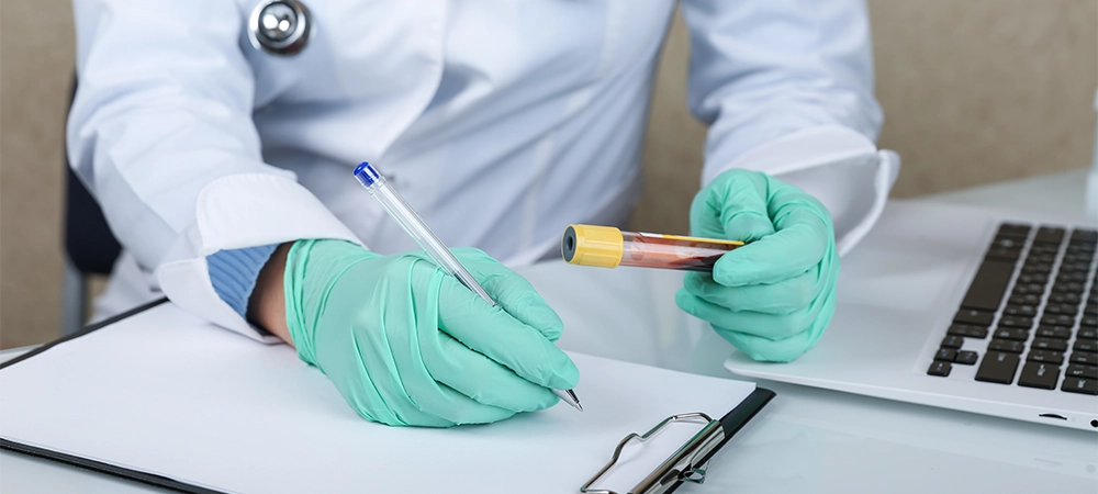 doctor holds blood test tube and fills a form close up