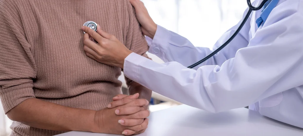 Doctor examining patient with stethoscope, performing medical check-up
