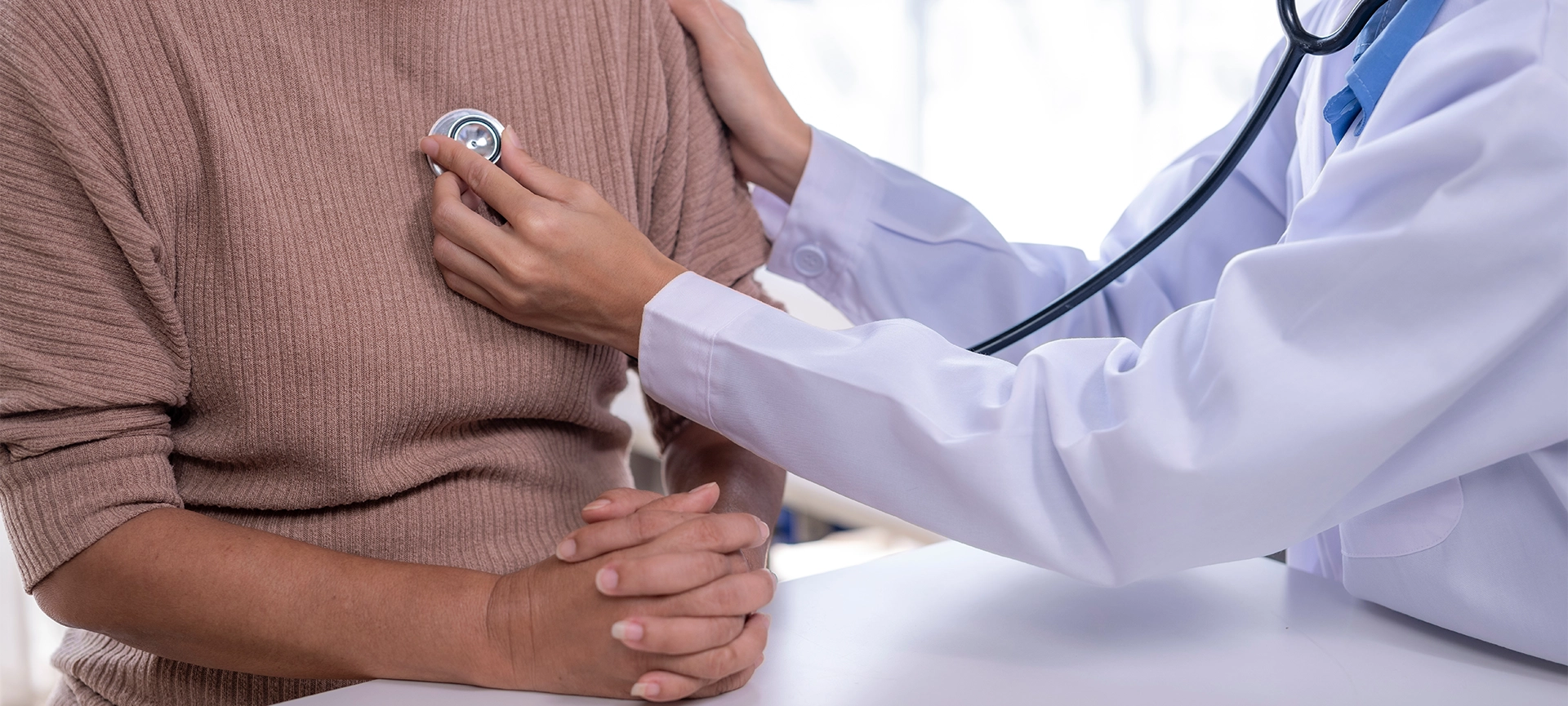 Doctor examining patient with stethoscope, performing medical check-up