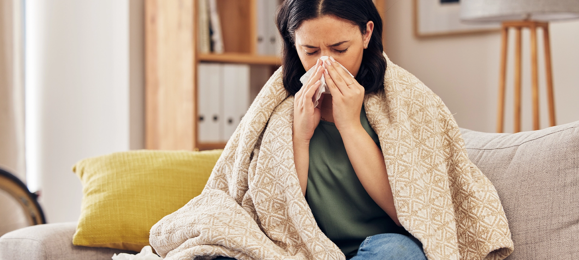 Tissue, blow nose and woman on sofa for home self care with virus, sick and healthcare or allergies. Sinus, flu and person on living room couch with allergy for medical or health and wellness risk
